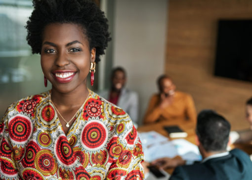 close up of beautiful young smiling professional black african business woman, coworkers hold a meeting in background
