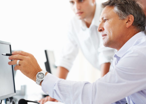Mature business man discussing project with his colleagues and pointing at computer screen